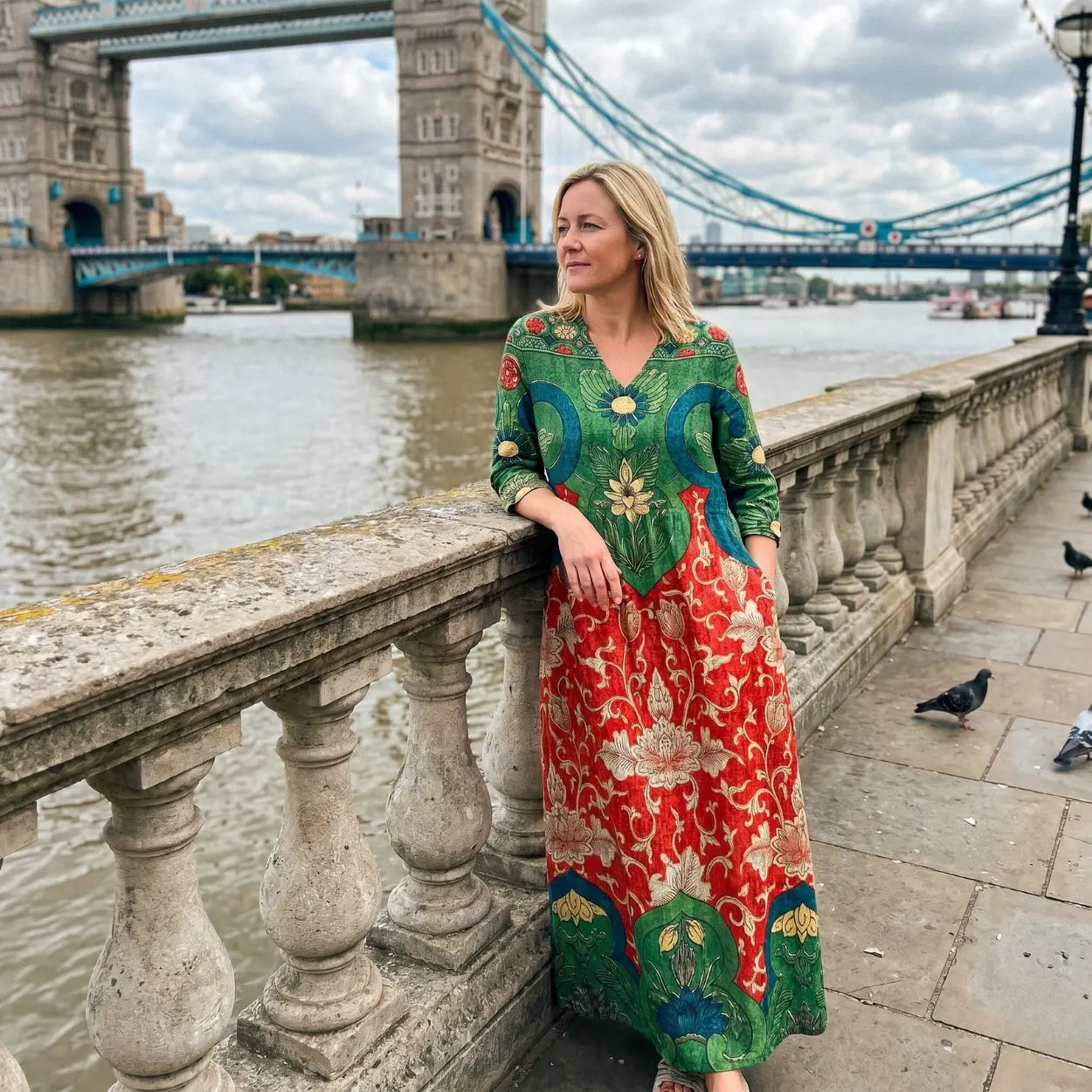 Woman in a colorful dress standing by the River Thames with Tower Bridge in the background
